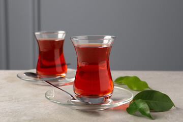 Glasses with traditional Turkish tea and green leaves on light grey table