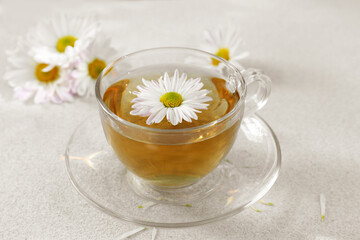 Glass cup of delicious chamomile tea on white table