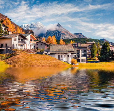 Cute houses of Maloja village reflected in calm waters of Sils lake, Switzerland, Europe. Splendid autumn scene of Swiss Alps. Traveling concept background.