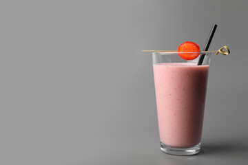 Glass with delicious berry smoothie on grey background. Space for text