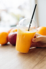 A glass of orange juice on a wooden in a field with fruits