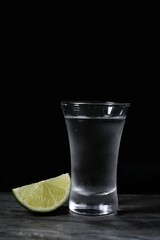 Shot of vodka with lime slice on grey table