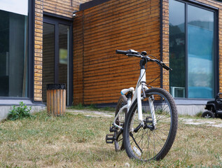 Fototapeta na wymiar new stylish house in the park. Vacation home in summer forest. Large windows. white modern bicycle on green grass.