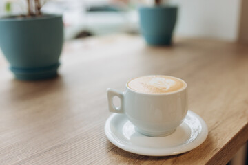Cup of coffee with heart pattern in a white cup on wood table
