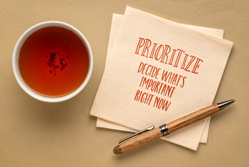 prioritize, decide what is important right now - inspirational advice or reminder on a napkin with a cup of tea, productivity and personal development concept