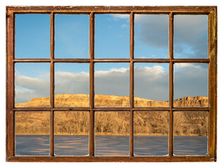 sunset light over a frozen lake and sandstone cliff at Colorado foothills, vintage sash window view