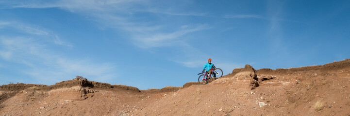 male cyclist is riding a gravel bike on cliff edge in Colorado prairie - Soapstone Prairie Natural Area, panoramic web banner