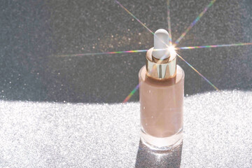 Beige foundation texture swatch. Cream drop with silver sparkles and pipette. Face skincare...