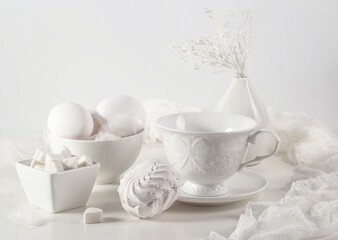 White still life with white dishes, eggs, sugar and marshmallows
