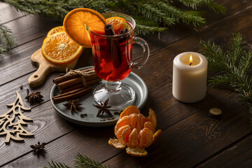 Christmas mulled wine and tangerines on a wooden table. Fir branches and a candle create a holiday mood