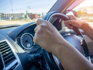 A man's hand held the steering wheel of a car to steer while the car was moving away. Concept and...