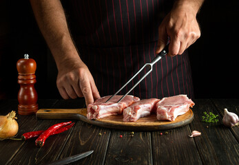 Professional chef cooking lunch with raw sliced meat steaks on the cutting board of the restaurant kitchen. Delicious grill idea.