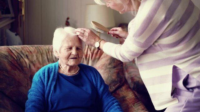 Woman combing hair of her elderly mother 
