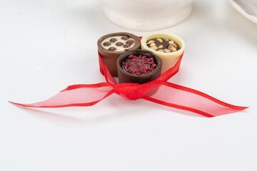 Chocolate temptation with delicious chocolate candies with red ribbon on a white background.
