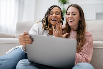 lesbian african american woman showing engagement ring near amazed girlfriend during video call.