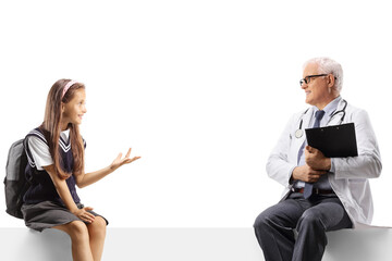 Schoolgirl sitting on a blank panel and talking to a male doctor