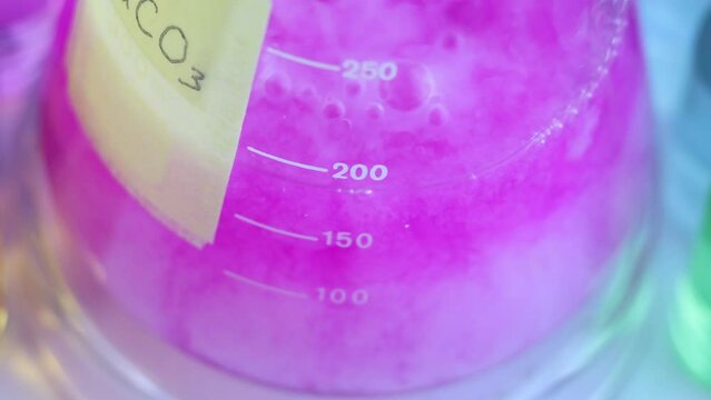 Chemical reaction of ion exchange in an aqueous solution. The formation of a white colloidal precipitate of calcium carbonate in a conical flask with the indicator dye phenolphthalein.