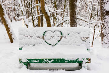 The outline of the heart on a snow-covered bench in the park.