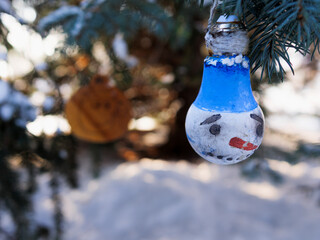 home-made toy from household waste on a Christmas tree covered with snow. homemade New Year's toys on the Christmas tree covered with snow. winter holiday decorations on the Christmas tree.