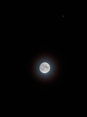 The hunter’s moon, full and surrounded by an iridescent halo of ice crystals in a cold autumn night sky.