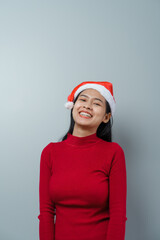 Pretty lovely lady asian thai women in red sweater and santa christmas hat isolated over grey background. hands pointing