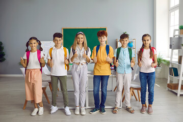 Children back to school. Happy group of schoolchildren ready for school showing thumbs up gesture...