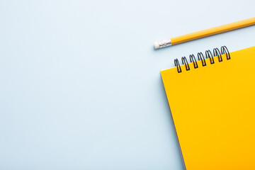 Yellow notebook with a pencil on a blue background, space for your text