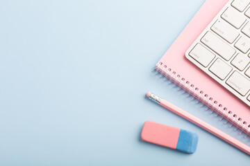 Pink notebook and pencil on a blue background. Place for your text