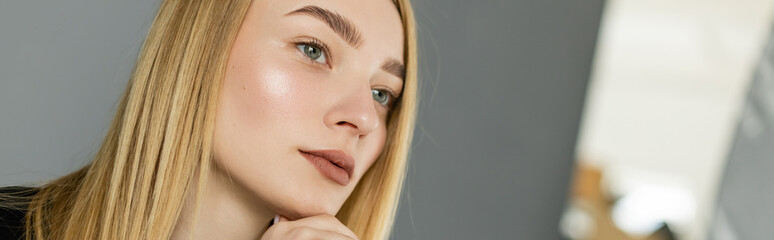 Obraz premium Young blonde woman looking at blurred mirror at home, banner.