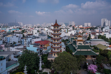 Buddhist temple and prayer tower in urban rooftop setting with view to city skyline on a sunny day...