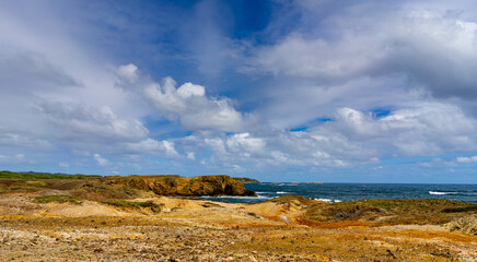 Multicolor sand landscape with ocean and blue sky and clouds