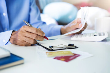 Stressed asian man checking and calculating receipt payment from credit card, monthly expenses,...