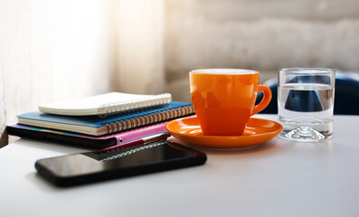 Close-up view, orange coffee cup with notebook placed on the tablet computer with smart phone and...