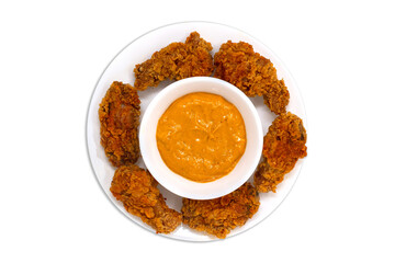 Golden brown crispy fried chicken pieces on white plate with peri peri dip sauce