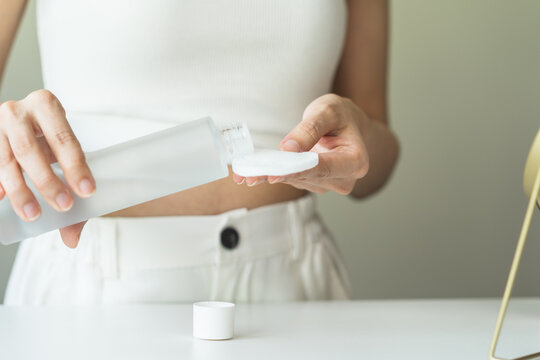 Close-up view hands of woman using toner and cotton pad to remove makeup
