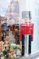 Shopwindow with Christmas decorations, gingerbread man, cakes, nutcracker, books, lighting. 
