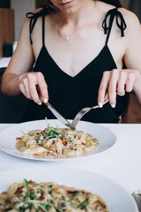 Obraz na płótnie Canvas woman tasting Italian food in restaurant, woman hands holing fork and knife eating food in restaurant
