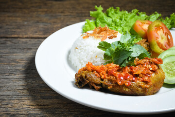 Ayam geprek sambal indonesian food or geprek fried chicken with sambal hot chili sauce served steam rice on white plate