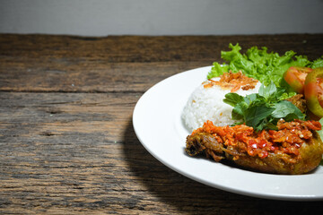 Ayam geprek sambal indonesian food or geprek fried chicken with sambal hot chili sauce served steam rice on white plate