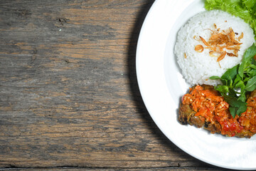 Ayam geprek sambal indonesian food or geprek fried chicken with sambal hot chili sauce served steam rice on white plate