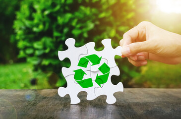 Hand picking jigsaw with recycle icon on natural background, Global efforts for recycling and environmental conservation concept.