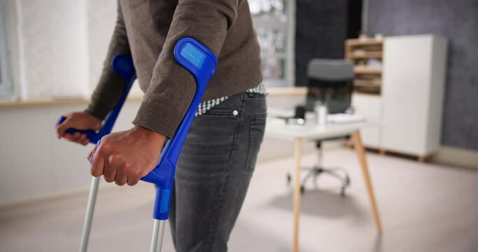 Worker With Crutches At Workplace Or Office