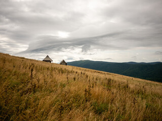 landscape in the mountains with two huts on the hill slope