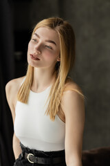 Fototapeta premium Blonde woman in white top looking away at home.