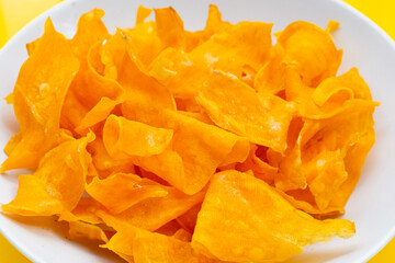 Sweet potato chips on yellow background.
