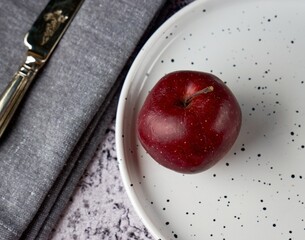 Czerwone jabłko na  białym talerzy - obrazy, fototapety, plakaty
