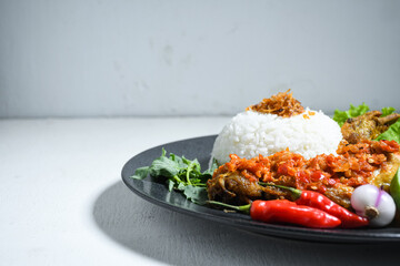 Ayam geprek sambal indonesian food or geprek fried chicken with sambal hot chili sauce served steam rice. Ayam Geprek is a typical Indonesian flour fried chicken dish that is pulverized or crushed
