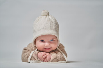 portrait of an infant in a white cap looking at the camera smiling