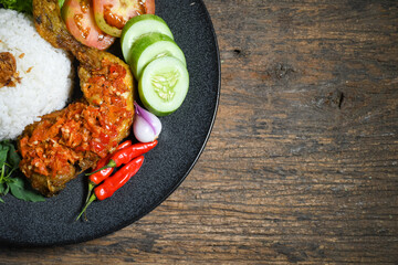Ayam geprek sambal indonesian food or geprek fried chicken with sambal hot chili sauce served steam rice. Ayam Geprek is a typical Indonesian flour fried chicken dish that is pulverized or crushed