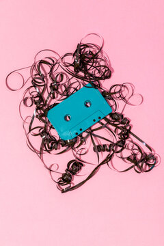 Retro cassette with tangled tape on pink surface